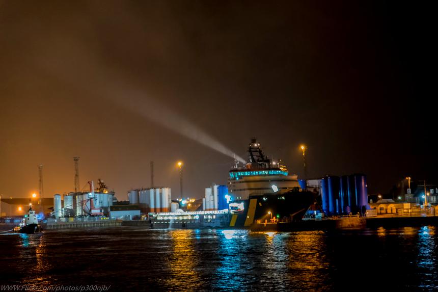 A supply vessel loading cargo under floodlights before an offshore run